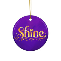 Glossy ceramic Christmas ornament with gold ‘Shine’ lettering on a midnight violet background, hanging from a gold string. Created by Women’s Fiction & Romance Author Juliet Gauvin.