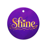 Glossy ceramic Christmas ornament with gold ‘Shine’ lettering on a midnight violet background. Created by Women’s Fiction & Romance Author Juliet Gauvin.