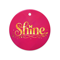 Glossy ceramic Christmas ornament with gold ‘Shine’ lettering on a mystic magenta background. Created by Women’s Fiction & Romance Author Juliet Gauvin.