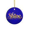 Glossy ceramic Christmas ornament with gold ‘Shine’ lettering on a midnight sapphire background, hanging from a gold string. Created by Women’s Fiction & Romance Author Juliet Gauvin.