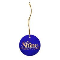 Glossy ceramic Christmas ornament with gold ‘Shine’ lettering on a midnight sapphire background, full gold string. Created by Women’s Fiction & Romance Author Juliet Gauvin.