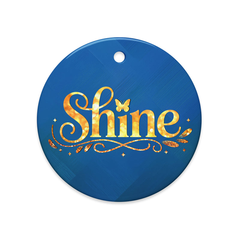 Glossy ceramic Christmas ornament with gold ‘Shine’ lettering on a midnight teal background. Created by Women’s Fiction & Romance Author Juliet Gauvin.