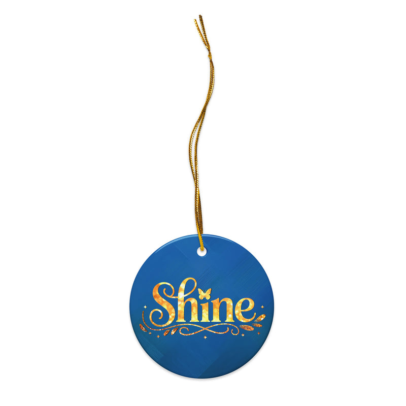 Glossy ceramic Christmas ornament with gold ‘Shine’ lettering on a midnight teal background, full gold string. Created by Women’s Fiction & Romance Author Juliet Gauvin.