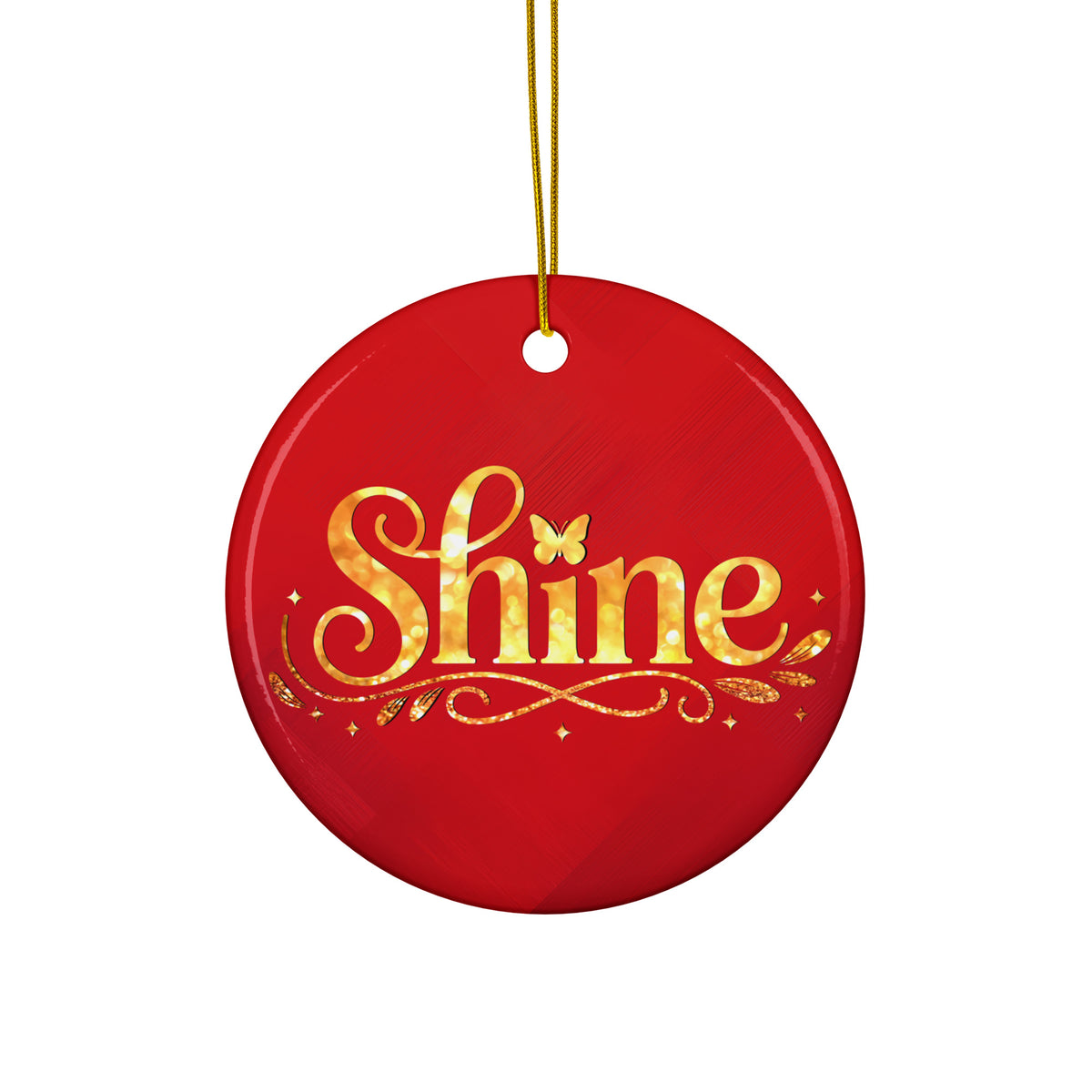 Glossy ceramic Christmas ornament with gold ‘Shine’ lettering on a mags red background, hanging from a gold string. Created by Women’s Fiction & Romance Author Juliet Gauvin.